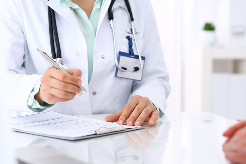 Ein Arzt berät einen Patienten und hat dabei ein Klemmbrett vor sich