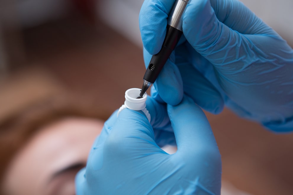 Spezialist hält Gerät zur Haarpigmentierung in der Hand