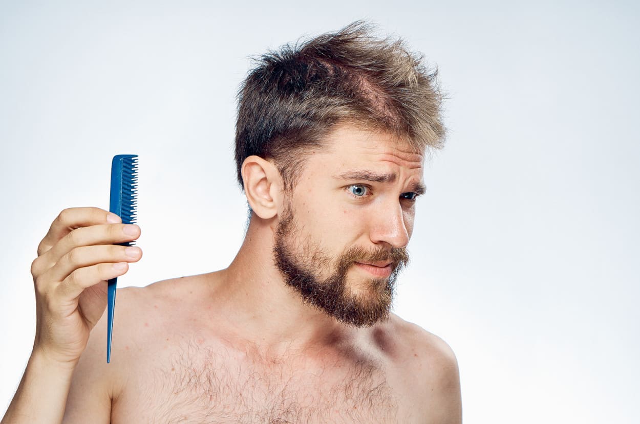 Mann kämmt sich die Haare und guckt verwundert.