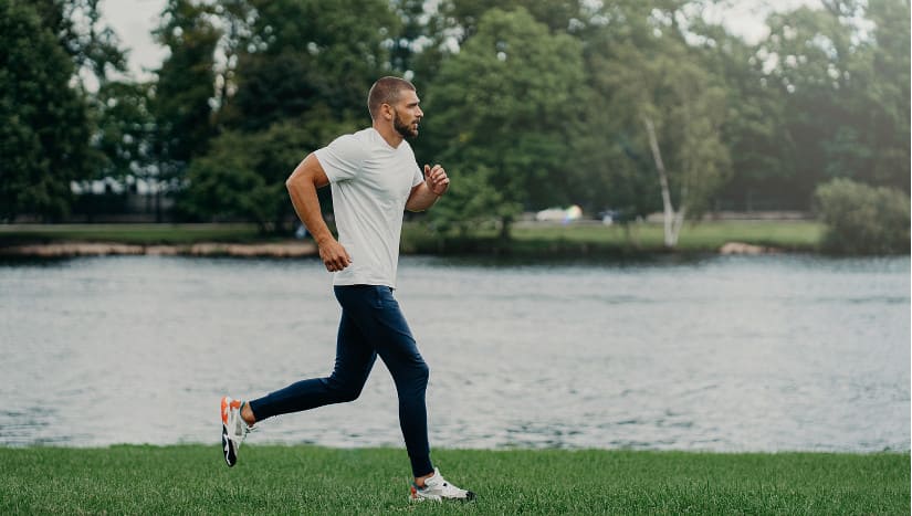 Junger Mann joggt am Wasser entlang.