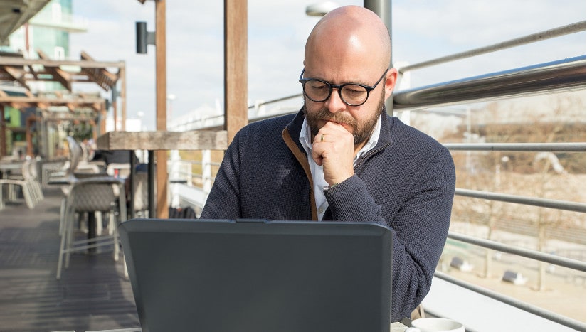 Mann mit Glatze guckt auf Laptop.