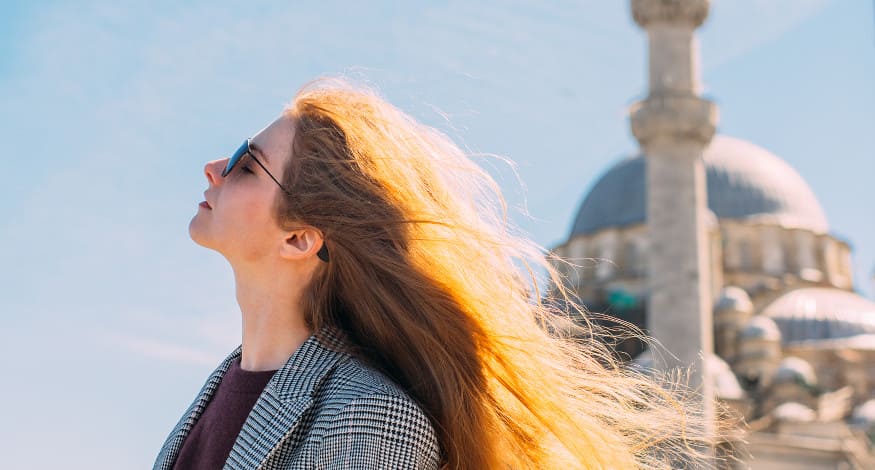 Frau mit Sonnenbrille in Istanbul schaut in die Sonne.