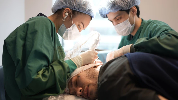 Bild zeigt, wie zwei Elithair Spezialisten bei einem Patienten eine Haartransplantation durchführen