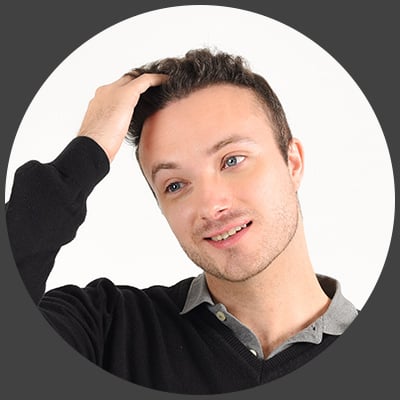 Patient greift sich mit der Hand in sein volles Haar nach der Haartransplantation in der Türkei