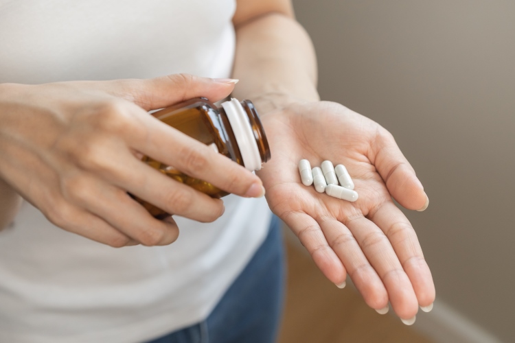 Priorin Kapseln gegen Haarausfall werden aus einem Glas in eine Hand geschüttet