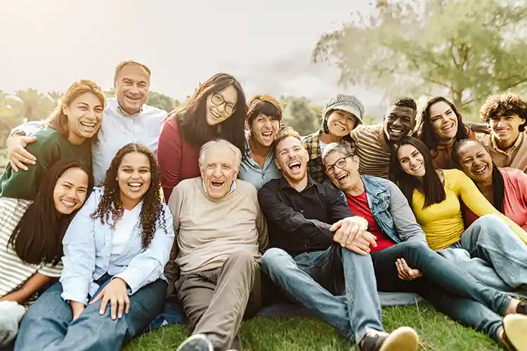 Eine Gruppe von Menschen in verschiedenen Altersgruppen und Ethnien umarmen sich und lachen zusammen