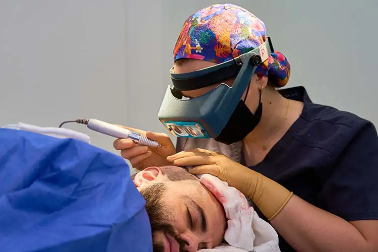 Ein Mann, liegend, bei einer Haartransplantation im OP-Saal