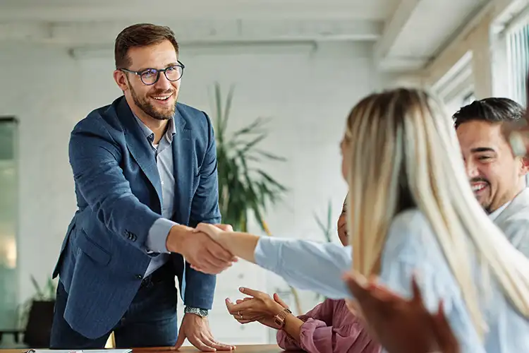 Ein Mann reicht lächelnd die Hand und wirkt selbstbewusst