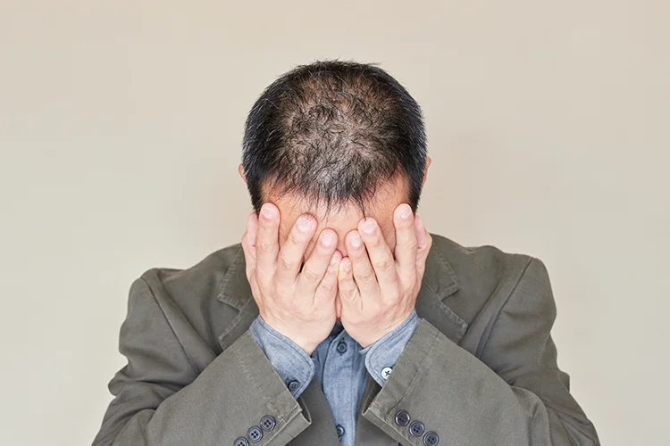 Ein Mann mit dem Kopf in den Händen wirkt enttäuscht – symbolisiert Frust und Verzweiflung
