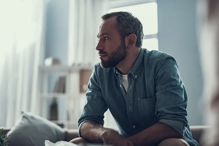 Ein Mann schaut nachdenklich zur Seite – seine Geheimratsecken sind deutlich sichtbar. Symbolisiert den stillen Umgang mit beginnendem Haarausfall und Unsicherheit.