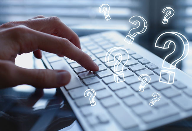 Hand tippt auf einer Computertastatur zur Erstellung von FAQ-Inhalten