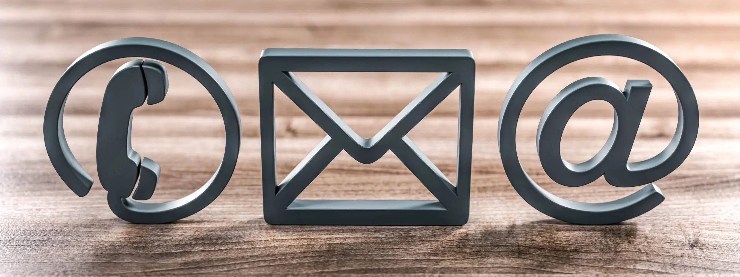 Kontakt-Symbole für Telefon, Brief und E-Mail auf einem Tisch