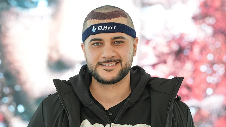 Hamed Loco trägt nach einer Haartransplantation ein Stirnband mit Elithair-Logo und lächelt in die Kamera.
