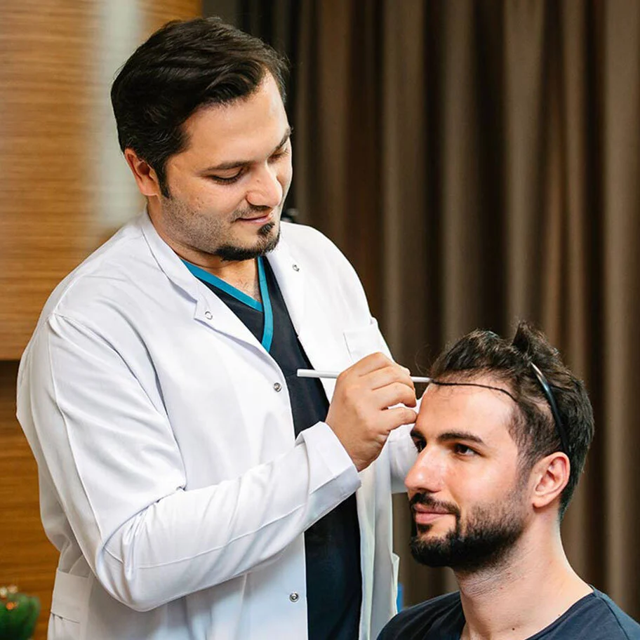 Arzt zeichnet individuelle Haarlinie am Patienten