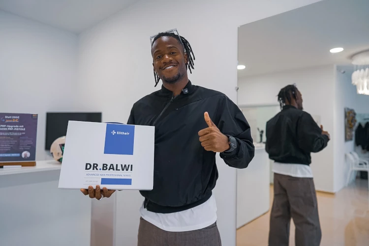 Profi-Fussballer Michy Batshuayi hält das Dr. Balwi Hair Boost Set in der rechten Hand und gibt mit der linken Hand den Daumen hoch